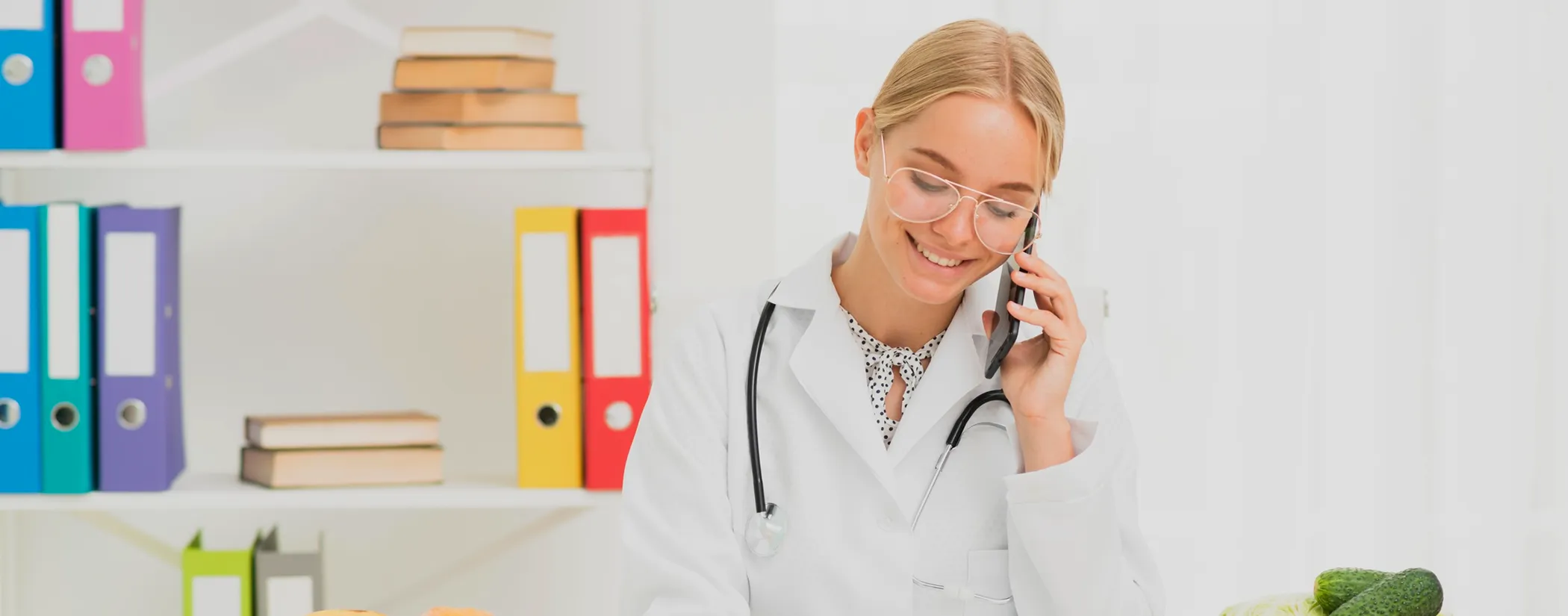 A smiling nutritionist in a white coat taking a phone call in her office